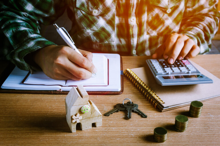 A man counting with a calculator with stacks of coins on the table.